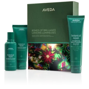 Aveda Bonds of Brilliance gift set features three green bottles of Botanical Repair hair products, perfect for winter hair care, elegantly arranged in front of a decorated box. | AMORE Salon, St. Petersburg, FL