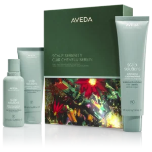 Aveda Scalp Solutions products, ideal for winter hair care, include a spray, shampoo, and exfoliating treatment in light blue packaging, displayed beside a green box with a colorful abstract design. | AMORE Salon, St. Petersburg, FL