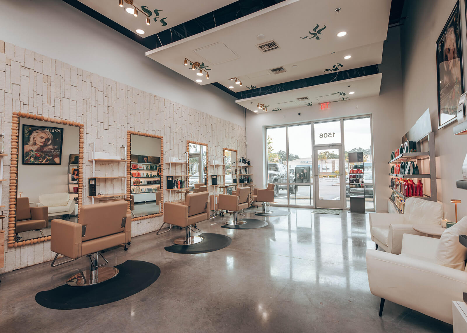 Modern hair salon interior with beige styling chairs, large mirrors, shelves with hair products, and a waiting area by the front glass doors. | AMORE Salon, St. Petersburg, FL